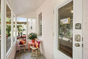 A cozy porch with a wooden table and chairs, a potted plant, and a view of the outside.