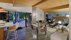 Un salon moderne doté d’une table à manger en verre, de sièges confortables, d’une cheminée et offrant une vue sur l’extérieur.