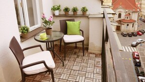Ein Balkon mit Korbstühlen, einem kleinen Tisch und Blumentöpfen.