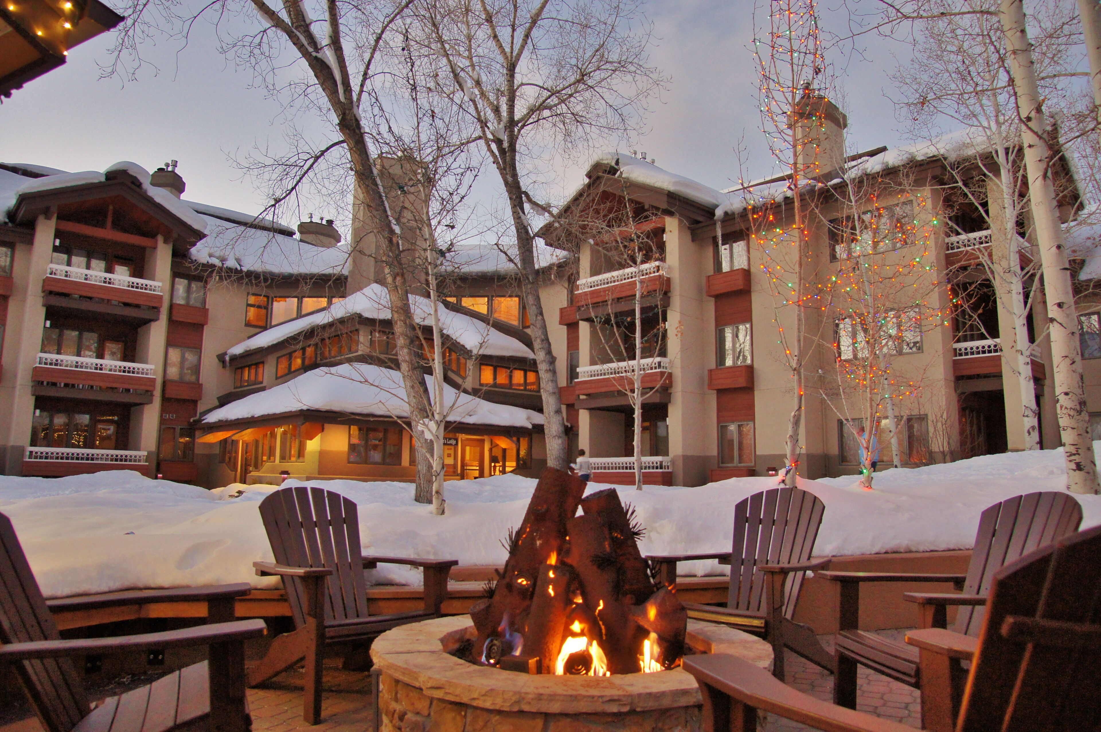 Een lodge met vuurkuil, buiten zitplaatsen en een besneeuwde omgeving.