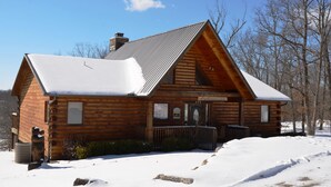 A log cabin with a snow-covered roof and a chimney, surrounded by a snowy landscape and leafless trees. - Elegant 2700 Sq Ft True Log Cabin-Private Hot Tub-Game Room-Pool Table-Best View Near Big Cedar (Ridgedale)