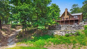 A rustic lodge with a stone retaining wall, a covered porch, and a disc golf course. - Elegant 2700 Sq Ft True Log Cabin-Private Hot Tub-Game Room-Pool Table-Best View Near Big Cedar (Ridgedale)