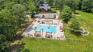 An aerial view of a resort with a swimming pool, lounge chairs, and a rustic building. - Elegant 2700 Sq Ft True Log Cabin-Private Hot Tub-Game Room-Pool Table-Best View Near Big Cedar (Ridgedale)