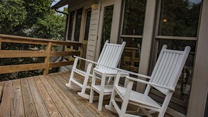 Une terrasse en bois avec trois chaises Adirondack blanches.