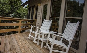 Une terrasse en bois avec trois chaises Adirondack blanches.