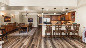Une cuisine spacieuse avec des meubles en bois, un îlot central doté de tabourets de bar et un coin repas avec une grande table et des chaises en bois.