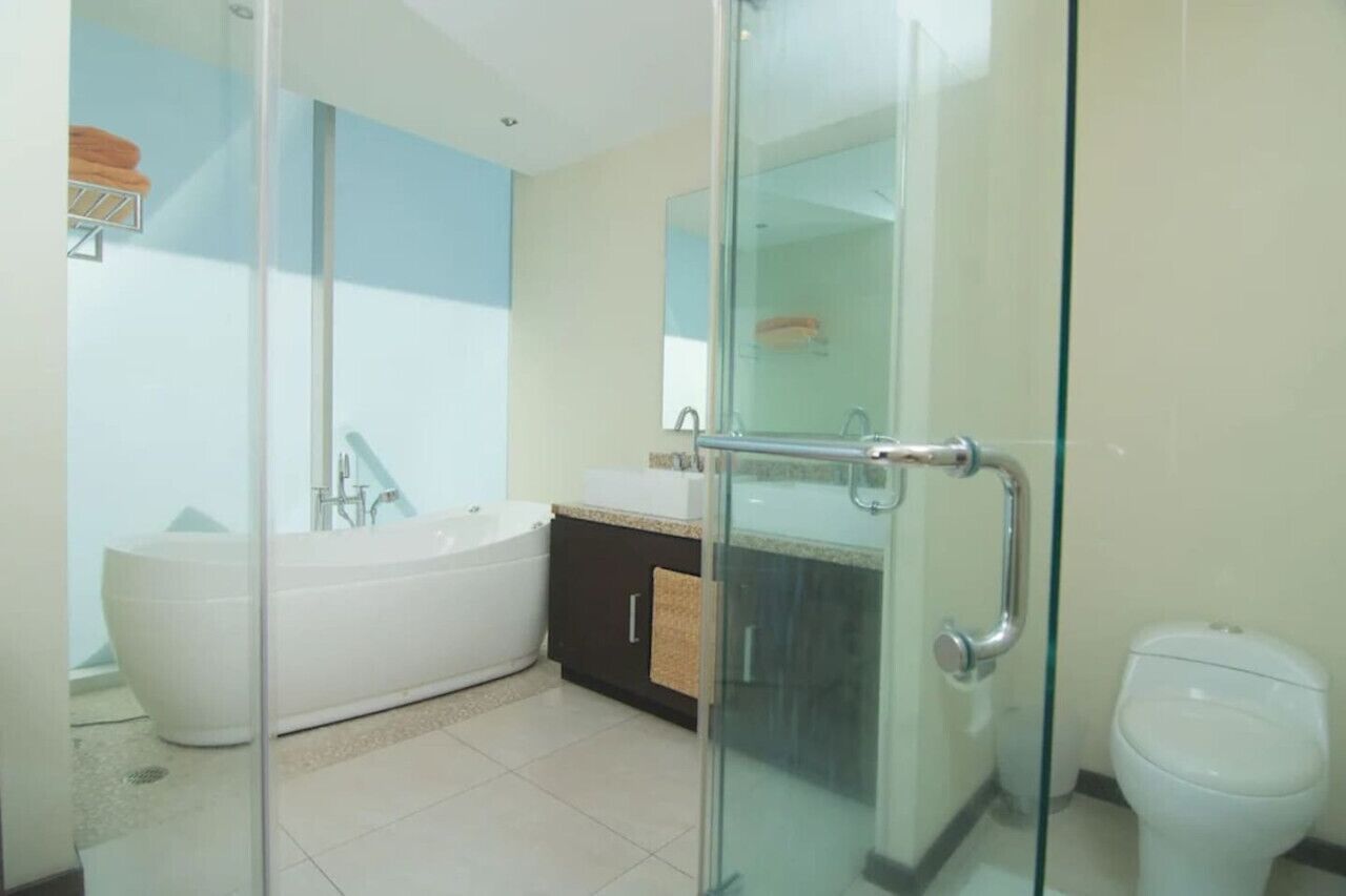 A modern bathroom with a glass shower enclosure, a freestanding bathtub, a sink with a mirror, and a toilet.