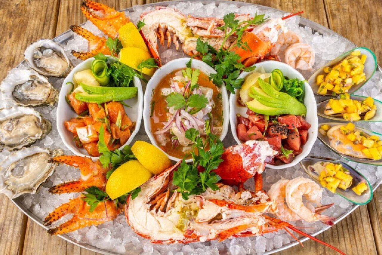 Een schaal met zeevruchten, zoals garnalen, kreeft en oesters, geserveerd op ijs.