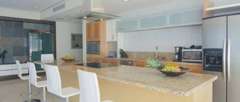 Una cocina moderna con una isla central, taburetes de bar y un refrigerador.