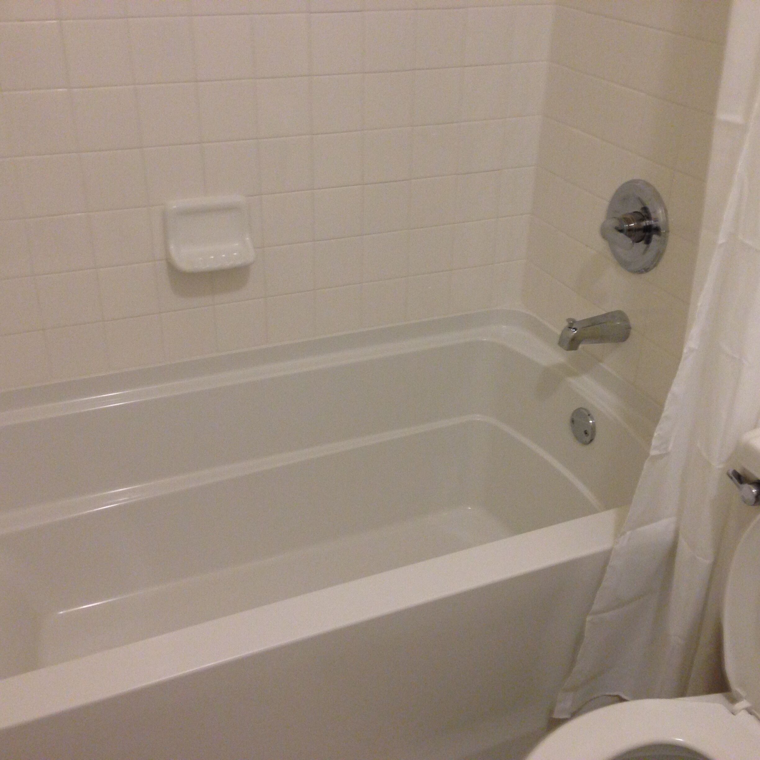 Une salle de bain avec une baignoire, des toilettes et une petite étagère.