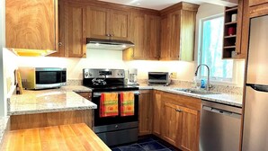 A modern kitchen with wooden cabinets, stainless steel appliances, and a tiled backsplash. - Newly Updated Spacious Home in Quiet Wooded Area (1246) (Wellfleet)