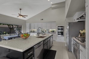 A modern kitchen with a large island, stainless steel appliances, and white cabinetry. - PGA West retreat with private pool, spa, and golf views. (La Quinta)