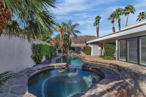 A swimming pool with stone edging, surrounded by palm trees and a mountain backdrop. - PGA West retreat with private pool, spa, and golf views. (La Quinta)