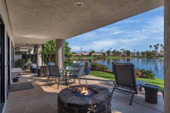 Une terrasse extérieure avec un foyer, des sièges et une vue sur un lac.