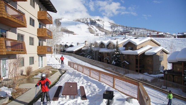 A ski resort with wooden buildings, a ski slope, and a wooden fence. - Easy Walk to Base Area Activities - Cozy Condo + Large Outdoor Hot Tub (Steamboat Springs)