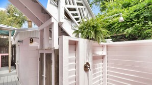 Une structure en bois peinte en rose, dotée d’une porte, d’une enseigne portant le chiffre « 9 » et d’un escalier menant à un balcon.