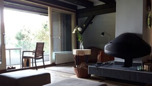A modern living room with a large window, a fireplace, and a comfortable seating area.