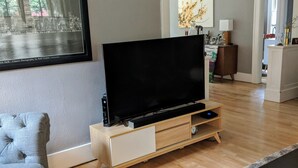 Una sala de estar moderna con un televisor de pantalla plana sobre un mueble de madera, un sofá gris y una alfombra estampada.