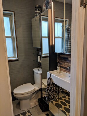 A compact bathroom with a toilet, sink, and mirror.