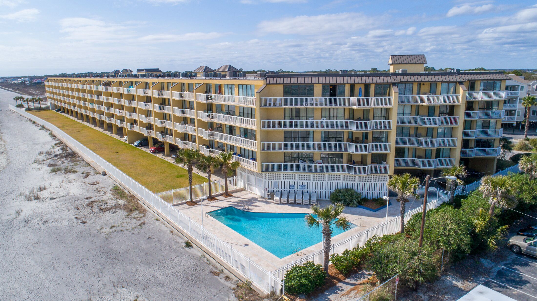Et hotel med flere etager, altaner, swimmingpool og udsigt til stranden.