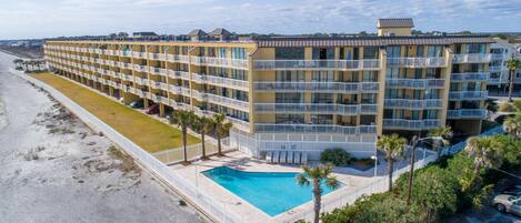 Et hotel med flere etager, altaner, swimmingpool og udsigt til stranden.