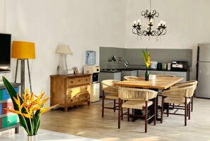 A modern kitchen with a dining area, featuring a wooden table and chairs, a chandelier, and a water dispenser. - Villa Umah JD Umalas spacious with private pool (Umalas)