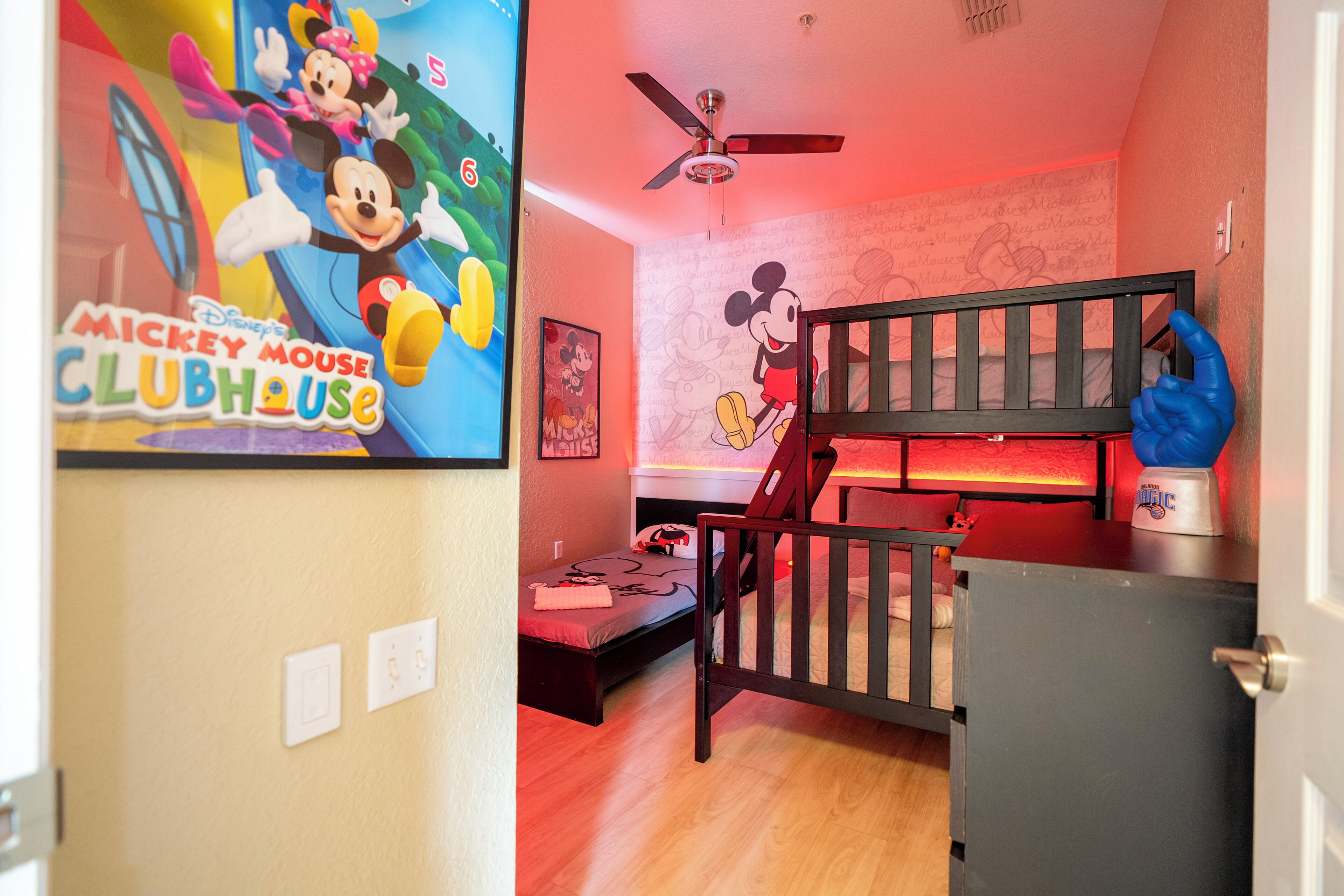 Habitación infantil con decoración de Mickey Mouse, camas literas y ventilador de techo.