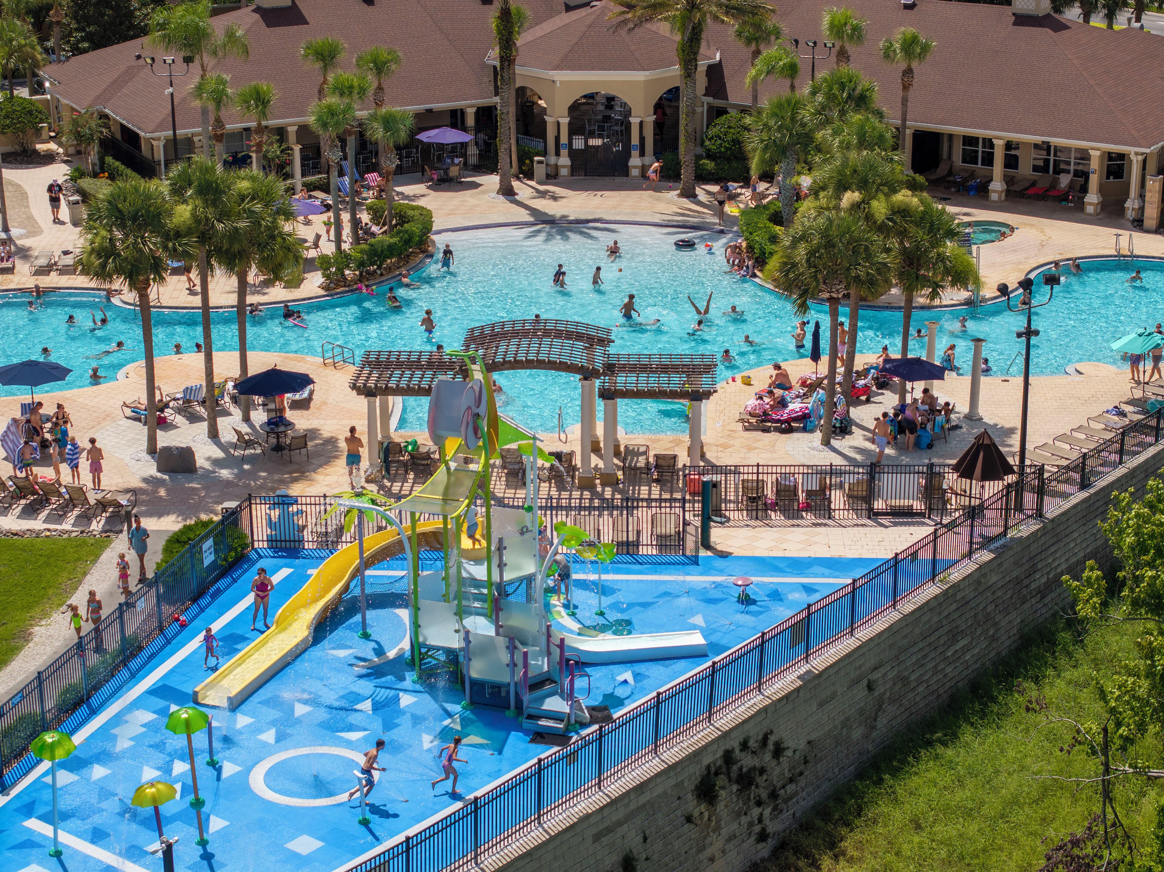 A large outdoor swimming pool with multiple lanes, a water slide, and a separate children's play area.