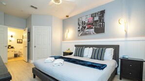 Ein ordentlich eingerichtetes Schlafzimmer mit einem großen Bett, Nachttischen und einem an der Wand hängenden Bild.