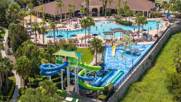 Ein Resort mit großem Pool, Wasserrutschen und einem überdachten Bereich mit Sonnenschirmen.