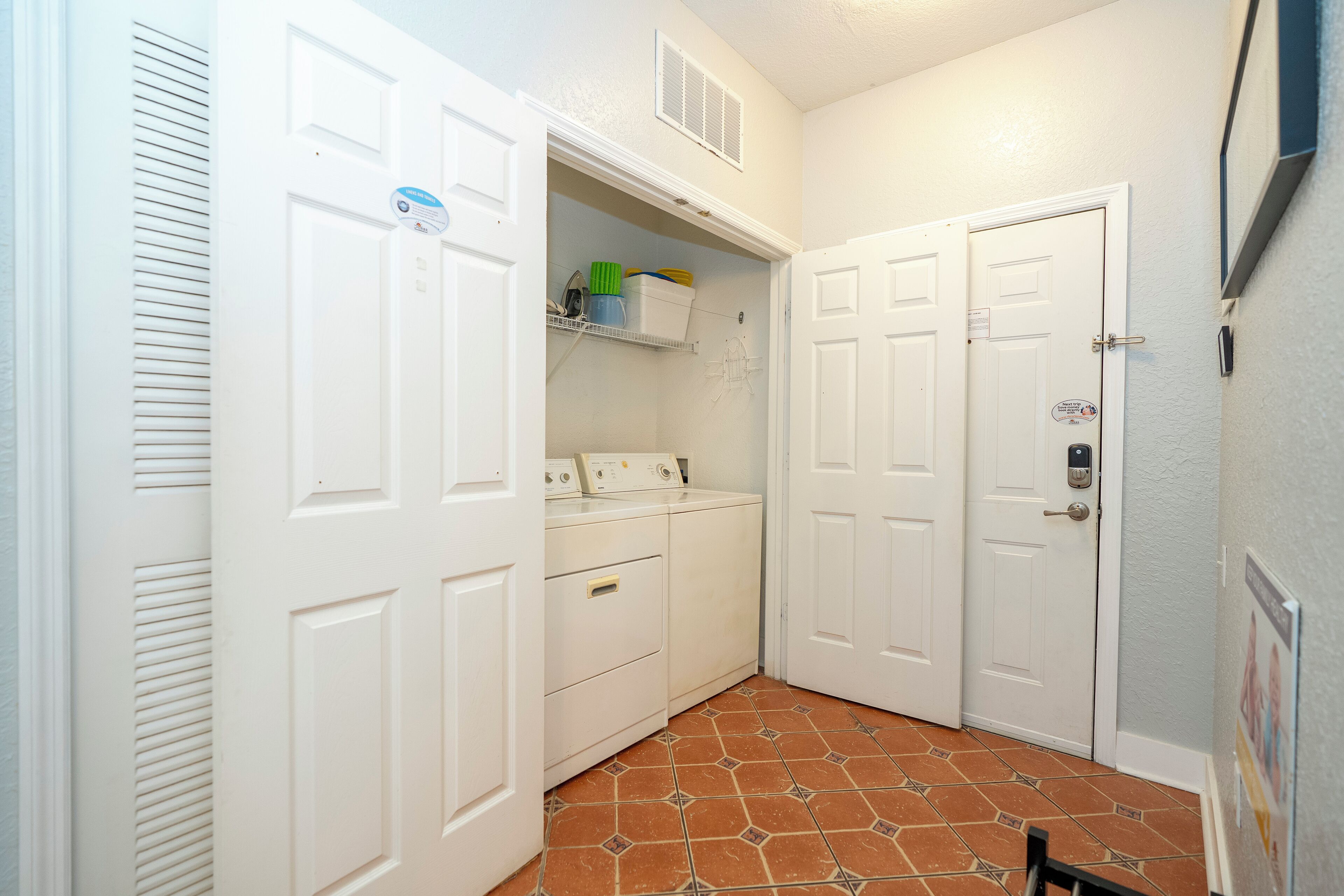 A laundry room with a washing machine, dryer, and shelves with laundry supplies.