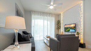 Ein modernes Wohnzimmer mit einer Couch, einem Couchtisch und einem an einer strukturierten Wand befestigten Fernseher.