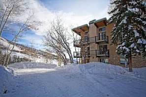 A multi-story building with balconies, surrounded by snow-covered ground and trees.