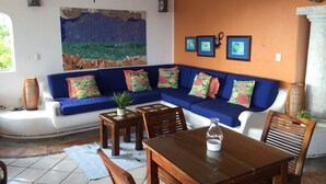 Uma sala de estar com um sofá azul, uma mesa de centro de madeira e um ventilador de teto.