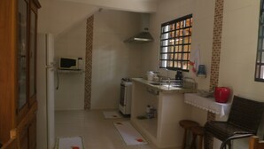A compact kitchen with a microwave, stove, and sink. There is a window with bars and a chair near the sink. - BEAUTIFUL HOUSE 5 MINUTES FROM THE CENTER – MONTE VERDE (Monte Verde)
