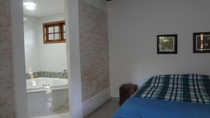 A bedroom with a bed, a wooden headboard, a small bedside table, and a wall-mounted picture frame. - BEAUTIFUL HOUSE 5 MINUTES FROM THE CENTER – MONTE VERDE (Monte Verde)