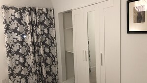 A bedroom with a bed, a wardrobe with glass doors, and a curtain with a floral pattern. - Beautiful updated apartment in a great location (Miami)