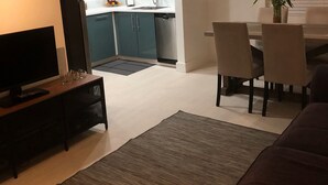 A modern living room with a flat-screen TV, a sofa, and a dining area with chairs and a table. - Beautiful updated apartment in a great location (Miami)