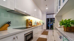 A modern kitchen with white cabinets, a built-in oven, and a countertop with various kitchen items. - AMAVI LUXURY - VINHOMES SPACIOUS AND COZY APT FOR FAMILY/GROUP - 4 BR  (Ho Chi Minh)