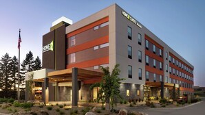 Un hotel moderno con techo plano, varios pisos y un área exterior cubierta con asientos.