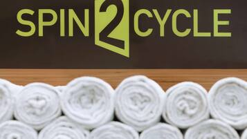 A sign with the text "SPIN2CYCLE" and a background of rolled towels.
