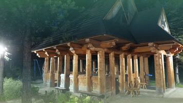 Une cabane en bois dotée d’un porche couvert et d’un espace extérieur aménagé pour s’asseoir.