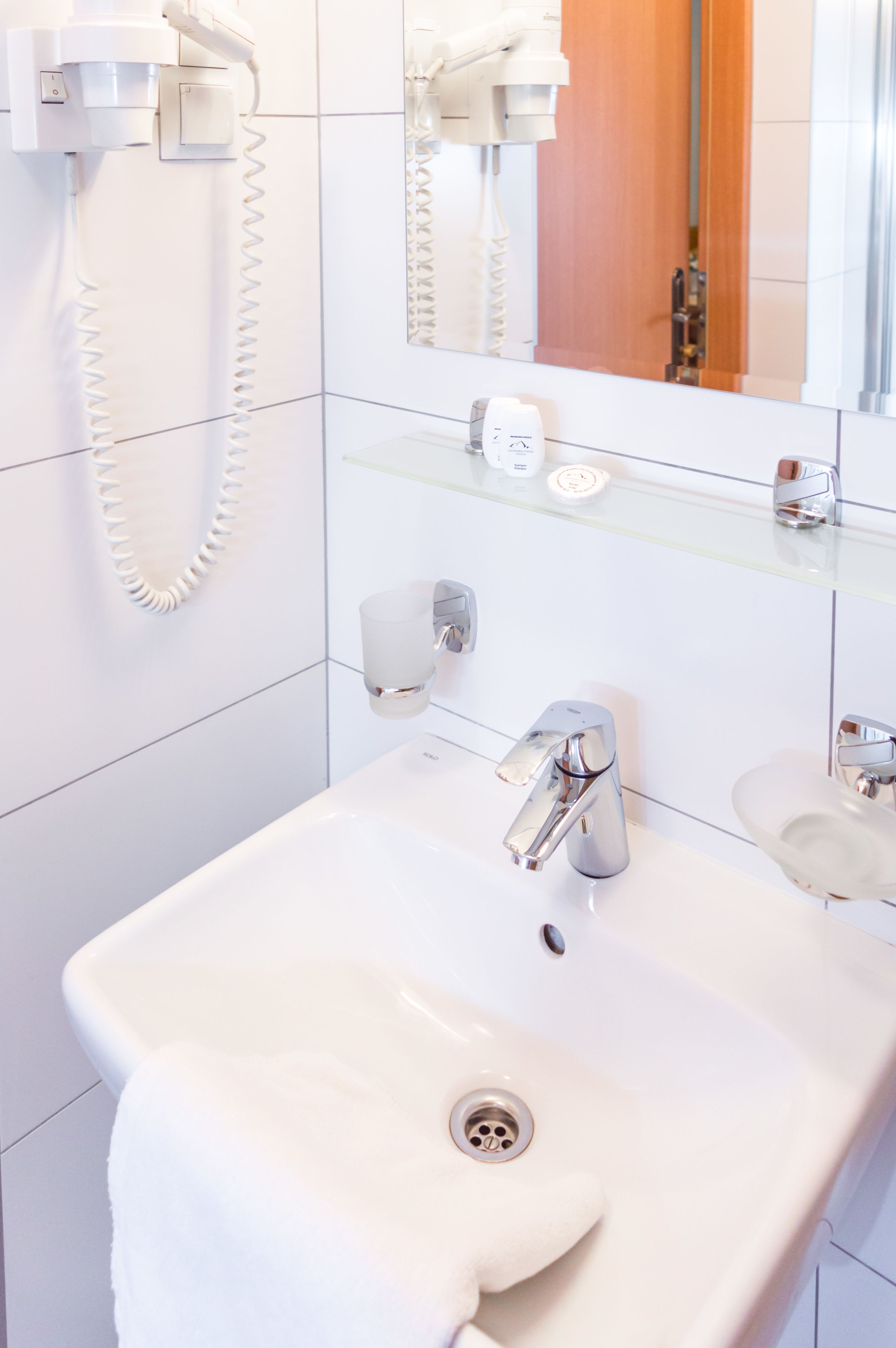 A modern bathroom with a white sink, chrome faucet, and a mirror above it.