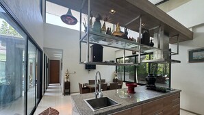 A modern kitchen with a large island, a built-in sink, and a glass partition.