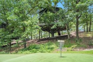 Een boomhuis gebouwd in een grote boom, omgeven door weelderige begroeiing en een golfbaan.