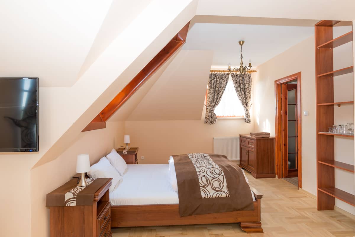 Ein Schlafzimmer mit einem hölzernen Bett, einem an der Wand befestigten Fernseher, einer Chandelüstere und einem Holzschrank.