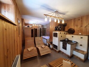 A wooden interior with a sauna, a kitchen, and seating areas. - Gosciniec Pieciu Stawow (Ustrzyki Dolne)