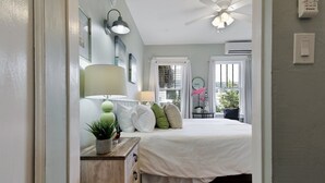 A bedroom with a bed, bedside lamps, a dresser, and a window with curtains.