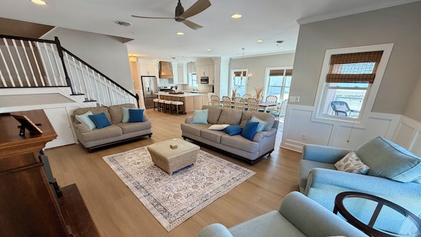 A spacious living room with a staircase, two sofas, a coffee table, and a dining area in the background. - Beach Block End Unit with Ocean Views From All Rooms!! (Wildwood Crest)