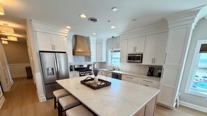 A modern kitchen with a large island, stainless steel appliances, and a view of the ocean. - Beach Block End Unit with Ocean Views From All Rooms!! (Wildwood Crest)